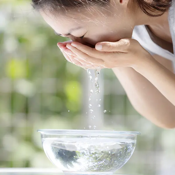 水で顔を洗う女性