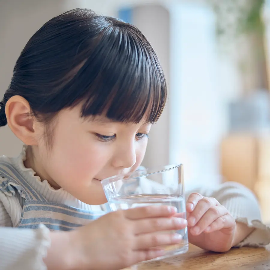 グラスで水を飲む女の子